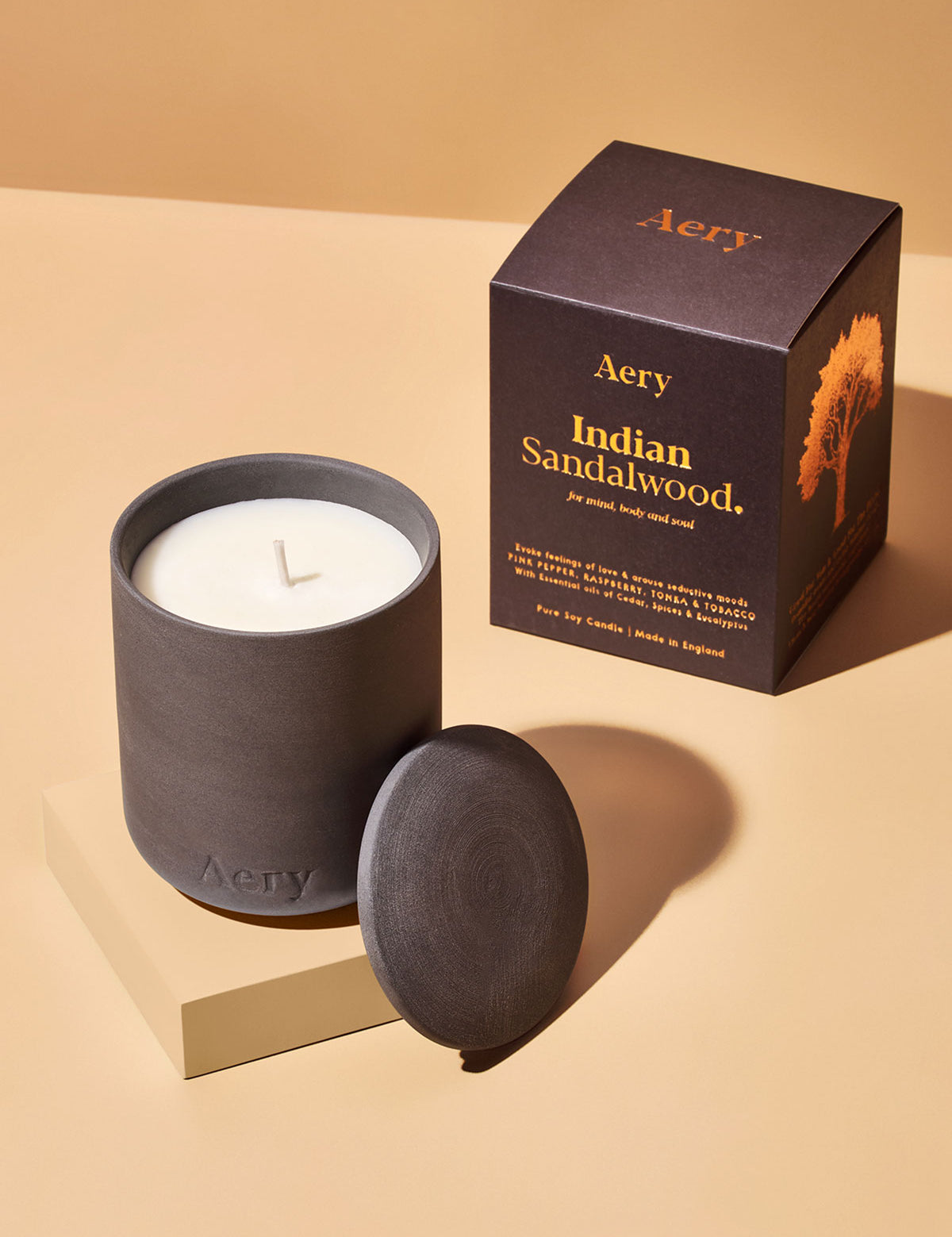 Aery Duftkerze 'Indian Sandalwood' in dunklem Keramikgefäß mit passendem Deckel und Verpackung mit Baumillustration;


