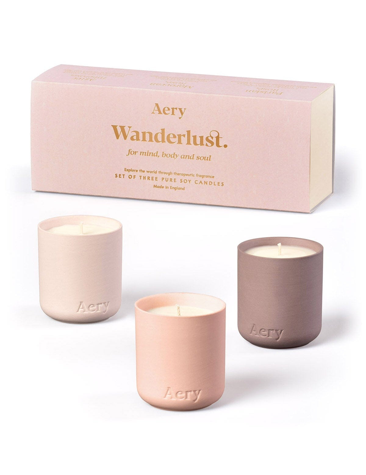 Geschenkset mit drei Aery Wanderlust Duftkerzen in pastellfarbenen Behältern aus Keramik vor rosa Verpackung;