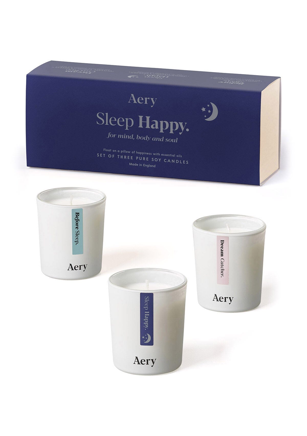Drei weiße Aromatherapie-Kerzen von Aery, Duftnamen 'Before Sleep', 'Sleep Happy' und 'Dream Catcher', vor dunkelblauer Verpackung mit Aufschrift 'Sleep Happy';