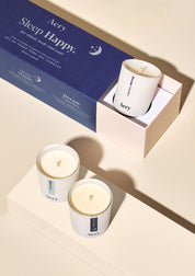 Drei weiße Duftkerzen von Aery mit Aufdrucken 'Before Sleep', 'Dream Catcher' und 'Sleep Happy' neben blauer Geschenkbox mit Text 'Sleep Happy Aromatherapy Set';