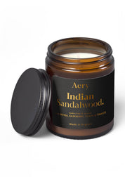 Braune Duftkerze im Glas mit schwarzem Deckel daneben, Marke Aery, Duft 'Indian Sandalwood' mit Noten von Pfeffer, Himbeere, Tonka und Tabak;