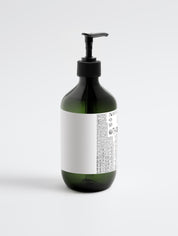 Grüne Flasche mit schwarzem Pumpverschluss und weißem Etikett mit kleingedrucktem Text;