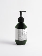 Grüne Flasche mit schwarzem Pumpspender und weißem Etikett mit kleingedrucktem Text;